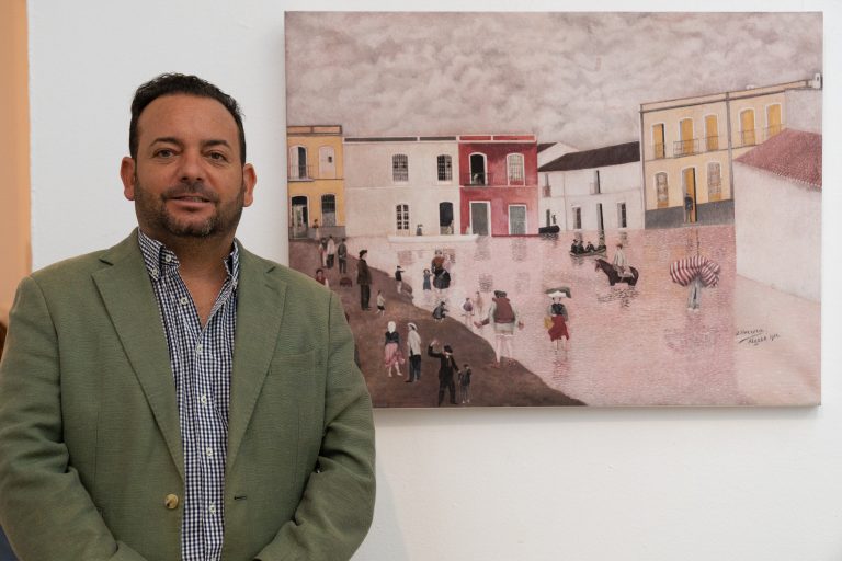 El alcalde de La Algaba posa con uno de los cuadros que forman parte de la exposici&oacute;n, el titulado La Riada, de Joaqu&iacute;n Herrera Carmona, boticario algabe&ntilde;o y v&iacute;ctima de la ca&iacute;da del puente